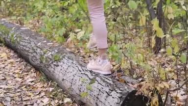 女游客穿着棕色靴子，背着背包在树林里的路上。 人行道上有橙色的落叶